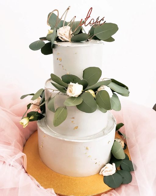 Zdjęcie przestawia złoty lustrzany cake topper z napisem miłość wbity w tort dekorację na tort