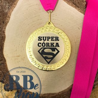 Zdjęcie przestawia złoty medal z różową szarfą logo superman i napisem super córka
